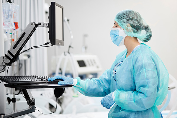 Doctor in scrubs and face mask working on medical machine