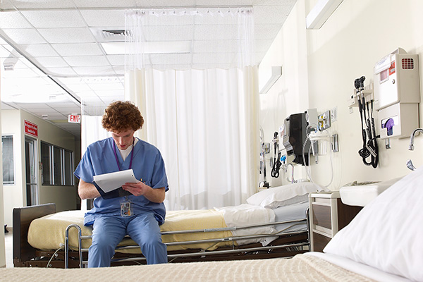 young doctor reading papers on hospital bed