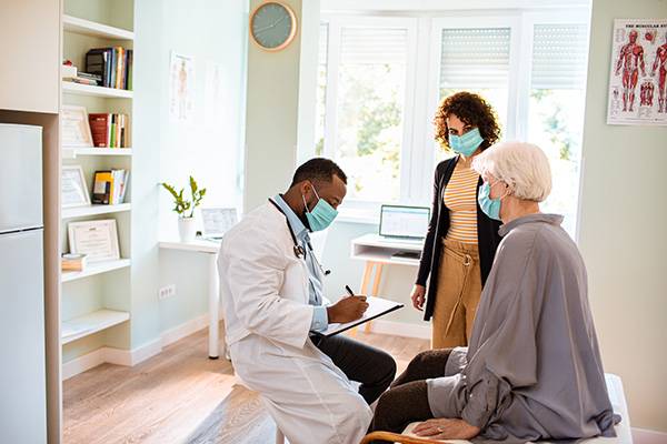 male doctor meeting elderly patient and adult daughter