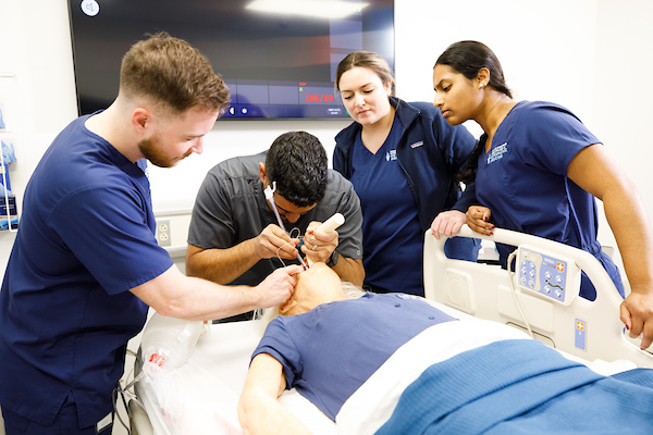 group of DO students working on a patient