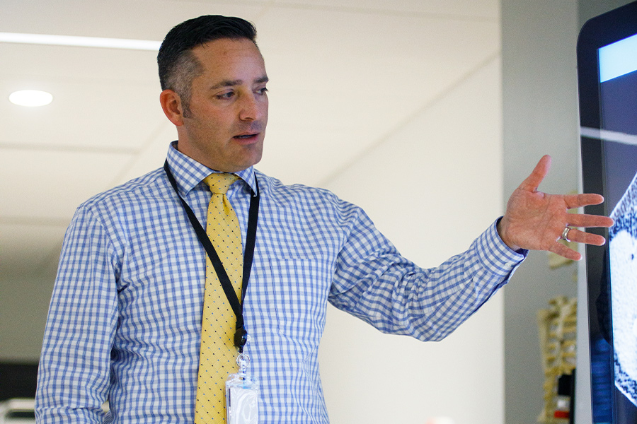 Teacher pointing at a television screen in front of a class