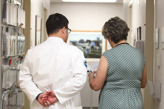 person in white coat talking with woman in patterned dress