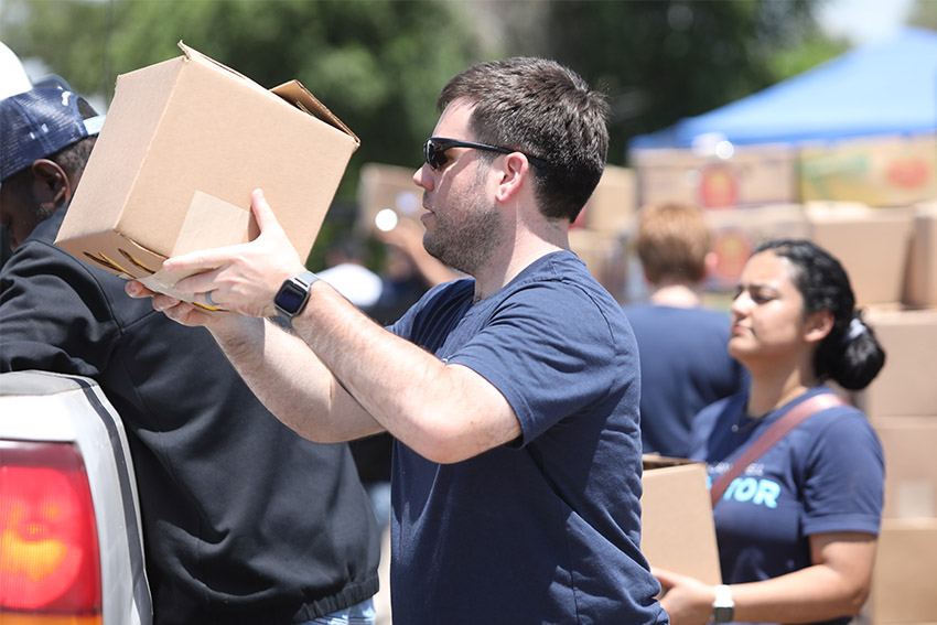 Students volunteering and stacking boxes in a truck.