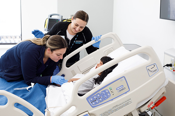 A DO student and teacher working on a patient