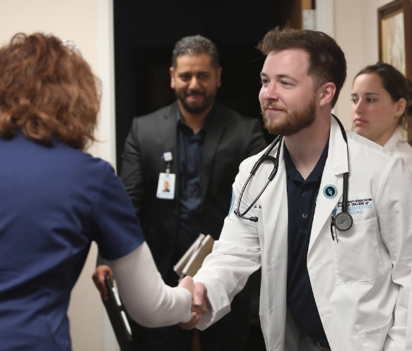 man in lab coat shaking hands with woman in scrubs