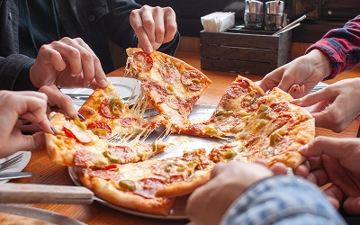 people pulling slices from a whole pizza
